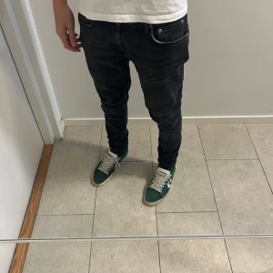 Svarta slim jeans från Nudie - Säljer ett par svarta jeans från Nudie med snygg tvätt. Jeansen har smal passform och sitter  längs benen. Tillverkade i stretchig bomullsdenim för komfort. W31 L32