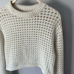 Vit stickad tröja från H&M XS - Säljer en vit stickad tröja från H&M i storlek XS. Tröjan har ett grovmaskigt, hålmönstrat stickat material och ribbad rund halsringning. Perfekt för lager-på-lager och ger en cool, avslappnad vibe.