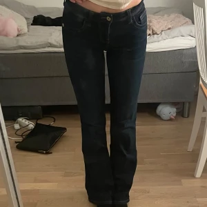 Mörkblå bootcut jeans - Snygga mörkblå low waist bootcut jeans från h&m i storlek 34. Klassisk femficksmodell med kontrastsömmar och coola detaljer på bakfickorna. Jeansen har låg midja och är tillverkade i mjukt denimtyg som sitter skönt hela dagen.