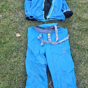 Blå täckbyxor från Action Wear 134/140 - Blå täckbyxor från Action Wear med justerbara hängslen och mjukt fleecefoder upptill. Byxorna har två stjärntryck på ena benet och är perfekta för kalla dagar utomhus. Snygg och praktisk design för dig som gillar att vara ute.