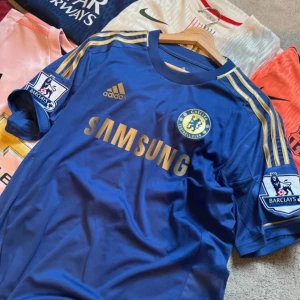 Chelsea retro hazard fotbollströja -  	•	Pris: 329 kr 	•	Skick: 10/10 	•	Storlek: M/S 	•	Lag/klubb: Chelsea 	•	År/säsong: 2012/13 	•	Färg: Blå, guld. 	•	Tryck: HAZARD 17