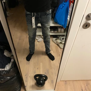 Blå slim jeans från Purple Brand - Säljer ett par blå jeans från Purple Brand i storlek 30. Jeansen har en slim passform med medelhög midja och snygga slitningar framtill. Klassisk femficksmodell med unika detaljer som stor vit tag på bakfickan. Perfekta för dig som gillar streetwear.