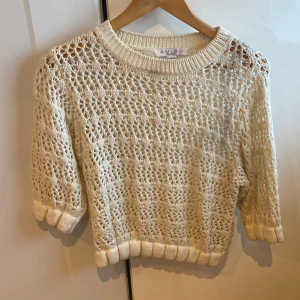 Stickad kortärmad tröja från Amisu - Säljer en ljusbeige stickad tröja från Amisu med korta ärmar och grovt virkat mönster. Tröjan har ribbade muddar vid ärmslut och nederkant, perfekt för vår och sommar. Snygg att styla över ett linne eller bralette.