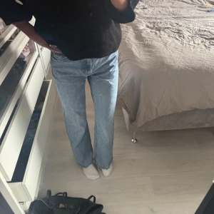 Zara jeans - Säljer ett par ljusblå jeans med rak passform och klassisk femficksdesign. Jeansen har hög midja och är tillverkade i ett robust denimtyg som ger en avslappnad och tidlös look. Perfekta för dig som gillar en enkel och clean stil.