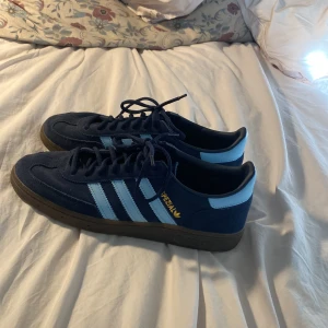 Adidas Spezial sneakers marinblå strl 43 - Säljer ett par Adidas Spezial sneakers i marinblå mocka med ljusblå ränder och detaljer som jag endast haft i en månad och säljer då dem för jag inte diggar dem så mycket men de är i hur bra skick som helst och därför det lite högre priset. Klassisk retrostil med gummisula och snörning. Perfekta för dig som gillar streetwear och vill ha en ikonisk look. Storlek 43 1/3 (US 9,5). Priset är ej hugget i sten!
