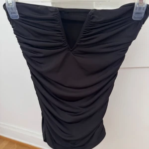 Svart topp  - Säljer en svart topp med snygg v-ringning framtill och rynkade detaljer.