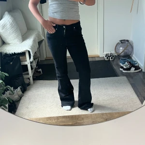 Svarta bootcut jeans - Säljer ett par svarta jeans med bootcut-modell och klassisk femficksdesign. Tillverkade i ett stretchigt jeansmaterial som sitter snyggt över höfterna och släpper ut vid benen. Perfekta för dig som gillar en tidlös och clean look.