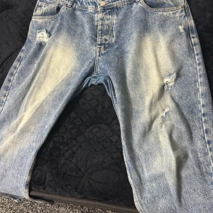 Blå slitna jeans från Armani - Säljer ett par blå jeans från Armani med slitna detaljer och ljusa tvättade partier. Jeansen har klassisk femficksmodell och raka ben. Perfekta för en avslappnad och trendig look.