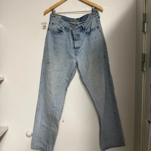 Levi's 501 ljusblå jeans straight fit W30 L 32  - Klassiska Levi's 501 jeans i ljusblå tvätt med raka ben och femficksmodell. Jeansen har knappgylf och den ikoniska läderpatchen bak i midjan. Perfekta för en avslappnad och tidlös look.