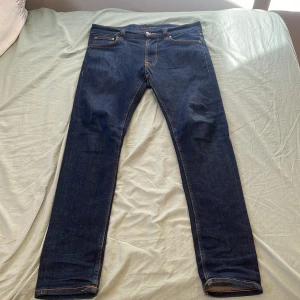 Nudie jeans lean dean - Snygga mörkblå jeans från Nudie Jeans med klassisk femficksdesign och kontrastsömmar. Jeansen har raka ben och normal passform, tillverkade i slitstarkt denimtyg av bomull. Bakfickorna har Nudie Jeans signaturbroderi i orange. Mitt pris är 449 men kan tänka mig att gå ner lite vid snabb affär. Kan skicka samma dag om beställning sker innan kl 15.                                  Storlek W29 L30