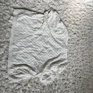 Vit kortärmad kofta  - Säljer en söt vit kortärmad kofta  med fint hålmönster och ribbade kanter. Koftan har knappar framtill och är gjord i mjuk stickad bomull, perfekt för lager-på-lager under vår och sommar.