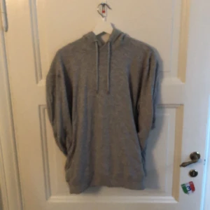 Grå hoodie med huva och snörning - Säljer en enkel grå hoodie med huva och snörning framtill. Tröjan har långärmade ärmar och en loose passform, perfekt för chill dagar. Materialet känns mjukt och skönt mot huden. Passar dig som gillar basic och avslappnad stil.