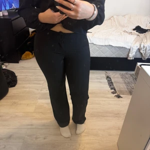 Svarta raka byxor med hög midja - Säljer ett par svarta byxor med hög midja och raka ben. Byxorna har två knappar framtill och sitter snyggt över höfterna. Perfekta för dig som gillar en klassisk och stilren look.