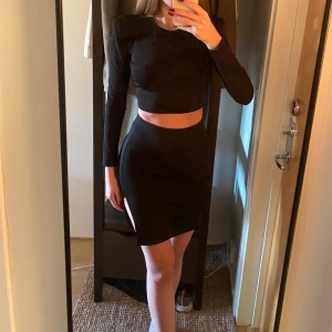 SET TOP & SKIRT - Säljer detta snygga set från Nelly trend.  Tröjan är långärmad & cropped. Den har även vadderade axlar. Kjolen är figurnära med slits på sidan. Kjolen är kort och har en stilren, minimalistisk design som sitter högt i midjan. Perfekt för dig som gillar en enkel men snygg look. Materialet känns stretchigt och bekvämt. 