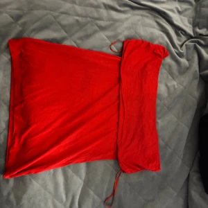 Röd offshoulder topp - Snygg röd topp med offshoulder-design och en axelbandslös look. Toppen har en enkel, tight passform och är tillverkad i ett mjukt tyg som känns bekvämt mot huden. Perfekt för dig som vill sticka ut med en färgstark och trendig stil.