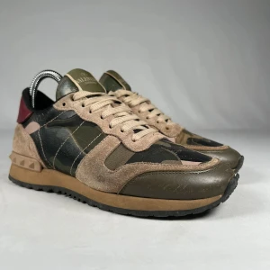 Valentino Rockrunner sneakers camouflage - Snygga Valentino Rockrunner sneakers med ikoniskt camouflage-mönster i grönt, beige och svart. Skorna har detaljer i mocka, skinn och textil samt nitar på hälen. Skorna är i storlek 37 men passar 38 och säljs för 1099kr. Väldigt bra skick och endast använda ett par gånger. Nypris på skorna är 5300kr