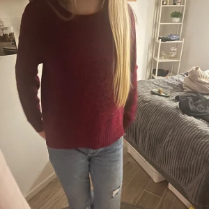 Vinröd stickad tröja - Mysig vinröd stickad tröja med rund halsringning och långa ärmar. Perfekt för kyligare dagar och enkel att matcha med jeans eller kjol. Tröjan har en klassisk passform och är superbekväm att bära.