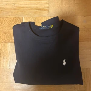 Svart sweatshirt från Polo Ralph Lauren - Säljer en snygg svart Ralph Lauren tröja. Perfekt skick på tröjan, nästintill oanvänd (ser ut som en fläck på en av bildena men det ät bara ljuset). Storlek S, jag är 183cm och sitter hyfsat bra bara lite för kort i armarna och längden. Bara att höra av sig vid frågor/pris!!