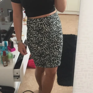 Svartvit mönstrad elastisk kjol - Säljer en svartvit tight kjol med abstrakt mönster. Kjolen är högt skuren i midjan och har en kort passform som sitter figurnära. Perfekt för dig som gillar en stilren men ändå iögonfallande look.