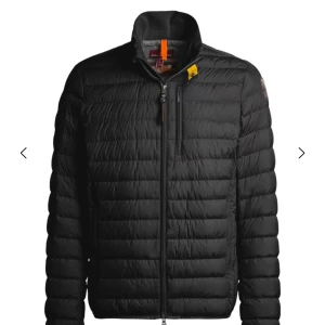 Svart dunjacka från Parajumpers - Svart dunjacka från Parajumpers med quiltad design, hög krage och dragkedja framtill. Jackan har en gul detalj vid halsen och en bröstficka med dragkedja. Perfekt för kyliga dagar och riktigt snygg till streetwear.