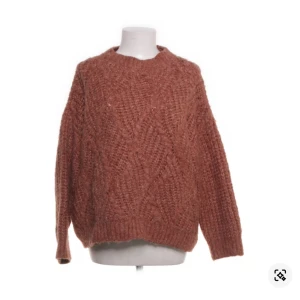 Brun stickad tröja från MNG Casual - Mysig brun stickad tröja från MNG Casual i storlek S. Tröjan har ett grovt stickat mönster med snygga detaljer och rund hals. Perfekt för lager-på-lager och chill höst- eller vinterstil. Långärmad och loose fit för en avslappnad vibe.