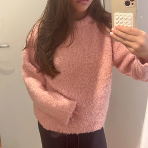 Fluffig rosa stickad tröja - Supermysig fluffig stickad tröja i ljusrosa färg. Tröjan har en loose passform, långa ärmar och är perfekt för kyliga dagar. Den är enkel men ändå riktigt söt och passar perfekt till jeans eller leggings.
