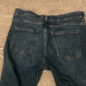 Blå bootcut jeans  - Säljer ett par klassiska blå jeans från Denim 1953 i modell bootcut. Jeansen har fem fickor, normal passform och är tillverkade i jeansmaterial. Perfekta för dig som gillar en tidlös look med lite utsvängda ben.