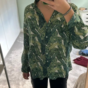 Tunn skjorta - Säljer en loose fit skjorta med tropiskt blad-mönster i olika gröna nyanser🤗Perfekt för dig som vill sticka ut med en färgstark och chill vibe!