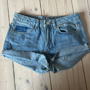 Blå jeansshorts från 2NDDAY - Säljer ett par klassiska blå jeansshorts från 2NDDAY, modell Stevie. De har ganska låg midja( ser läggre ut på ), uppvikta benslut för en mer känsla av micor shorts. Shortsen har fem fickor och bälteshällor, perfekta för sommardagar. Har gjort om dem till shorts!💕
