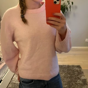 Ljusrosa stickad tröja Gina Tricot - Supermjuk ljusrosa stickad tröja från Gina Tricot i ullblandning. Tröjan har rund halsringning, ribbade muddar och lång ärm. Perfekt för lager-på-lager och ger en söt vibe till din outfit.