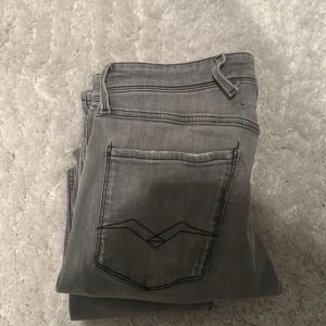 Grå jeansbyxor med svart söm - Snygga grå jeansbyxor med svart dekorativ söm på bakfickan. Klassisk femficksmodell med bälteshällor och raka ben. Perfekta för dig som gillar en stilren och enkel look.