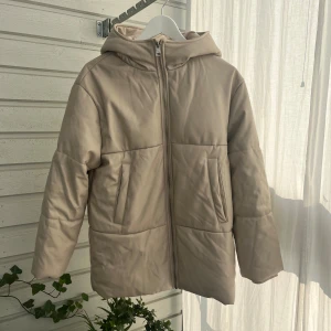 Beige pufferjacka med huva från Zara - Säljer en beige pufferjacka från Zara i storlek 164. Men motsvarar en xs/s! Jackan har en stor huva, två snedställda fickor framtill och dragkedja hela vägen upp. Mjuk och skön med ribbade muddar vid ärmsluten. Perfekt för kyliga dagar.