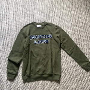 Olivgrön sweatshirt Les Deux S - Olivgrön sweatshirt från Les Deux med trycket 'Quartier Latin' i blått och vitt framtill. Använd en gång storlek S.