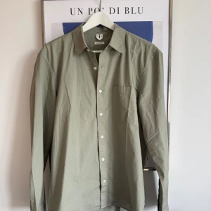 Ljusgrön skjorta från Arket - Snygg ljusgrön skjorta från Arket i regular fit. Skjortan är tillverkad i bomull, har klassisk krage, bröstficka och vita knappar framtill. Perfekt för en clean och stilren look.