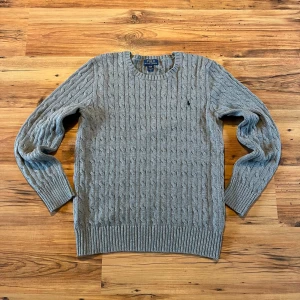 Grå kabelstickad tröja Polo Ralph Lauren - GråKabelstickad Polo Ralph Lauren size S 🐎  - längd (64cm), bredd (46cm), ärm (61cm)         10/10 skick, knappt använd, inga defekter            Hör av er 🫡