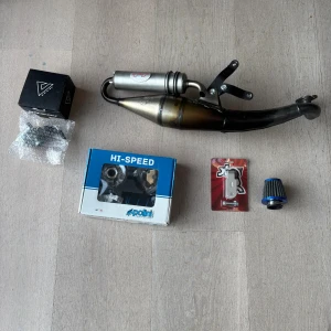 Polini Hi-Speed Variator Kit & TT Exhaust - Komplett Polini Hi-Speed variatorkit, TT avgassystem, sportluftfilter och tillbehör. Delarna är i gott skick, vissa är nya i förpackning. Perfekt för trimning och uppgradering av mopedens prestanda. Inga synliga defekter eller större slitage.