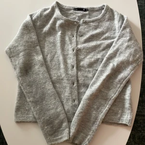 Grå kofta med knappar - Mysig grå kofta från H&M med rund halsringning och knäppning framtill. Långärmad och stickad i mjukt material, perfekt för lager-på-lager. Enkel och stilren design som passar till det mesta.