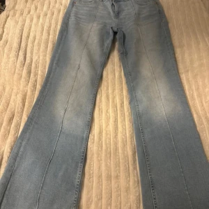 Ljusblå bootcut jeans med pressveck - Säljer ett par ljusblå jeans med bootcut-modell och markerade pressveck längs benen. Jeansen har klassisk femficksdesign och är tillverkade i mjukt denimtyg. Perfekta för dig som gillar en retroinspirerad look med lite extra vidd nertill.