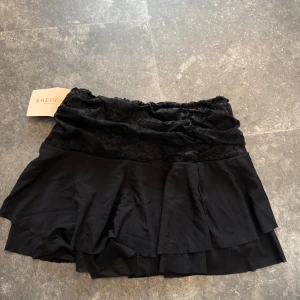 Svart volangkjol med spets  - Den har inbyggda shorts och är ny med prislapp.