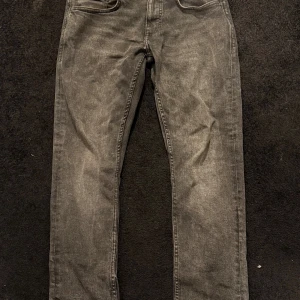 Grå jeansbyxor i rak modell - Säljer ett par grå jeansbyxor i rak modell. Byxorna har en snygg tvättad look och normal passform. Perfekta för dig som gillar en enkel och stilren stil. Midjan är normal och materialet är klassisk denim.