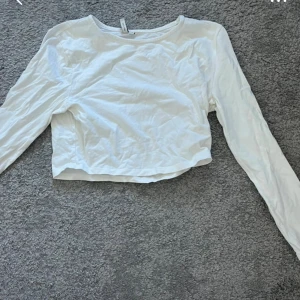Vit croppad långärmad topp - En enkel och stilren vit croppad topp med långa ärmar och rund halsringning. Perfekt att matcha med jeans eller kjol för en clean look. Tillverkad i mjuk bomull som känns skön mot huden.