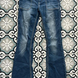 Blå bootcut jeans från Peacebird - Snygga blå jeans från Peacebird med bootcut-modell och markerade sömmar. Jeansen har stora framfickor och klassiska bakfickor. Materialet är jeans i bomull och passformen är normal. 