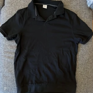 Svart kortärmad skjorta från Zara - Svart skjorta från Zara i storlek S med klassisk krage och korta ärmar. Skjortan har en stilren och enkel design utan mönster, tillverkad i mjukt bomullsmaterial som känns skönt mot huden. Perfekt för dig som gillar minimalistisk stil och vill ha något som funkar till många olika looks.