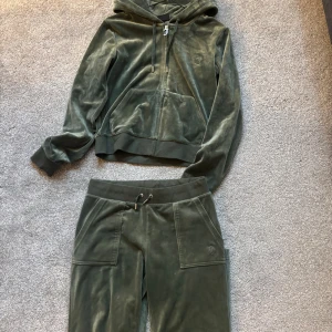 Grönt mjukis set från Juicy Couture - Mörkgröna mjukisbyxor från Juicy Couture i mjuk sammet med bred resår och snörning i midjan. Byxorna i storlek s och tröjan i storlek m