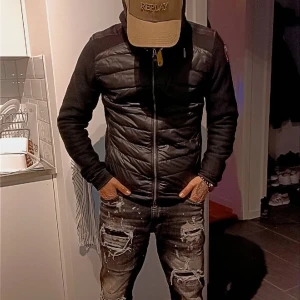 Svart pufferjacka från Parajumpers riktigt fin - Svart pufferjacka från Parajumpers med quiltad front och huva. Jackan har en gul detalj vid halsen, dragkedjor på bröstet och sidan samt ett snyggt Parajumpers-märke på ärmen. Materialmix med polyester och syntet, perfekt för kyliga dagar. Tagit väl hand om den fick den i present för 2 år sen nypris 4999  st S/m så klart äkta !