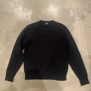 Marinblå stickad tröja från Uniqlo XS - En stilren svart stickad tröja från Uniqlo i storlek XS. Tröjan har rund halsringning, ribbade muddar och är långärmad. Perfekt för lager-på-lager och enkel att matcha med allt i garderoben. Washable Milano Ribbed Crew Neck Jumper från uniqlo.
