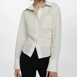 Linneskjorta med draperad detalj - Helt oanvänd. Snygg och stilren skjorta i bomulls- och linnemix. Draperad detalj på sidorna för att skapa form och siluett. Ordinarie pris 749kr.