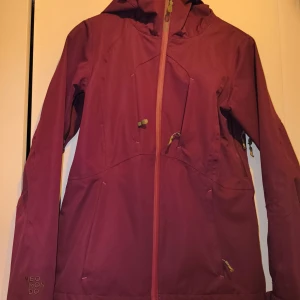 Vinröd vindjacka från Neomondo XS - Snygg vinröd vindjacka från Neomondo i storlek XS. Jackan har huva, flera praktiska fickor med dragkedja och coola detaljer i kontrastfärg. Perfekt för dig som gillar att vara ute och vill ha en jacka med schysst passform och stilren look.nästan ny