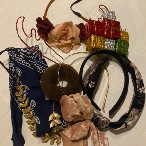 Paket med 7 diadem och hårband - Säljer ett mixat paket med sju diadem och hårband: ett diadem med röda glittriga renhorn, ett svart diadem med färgglada julklappspaket, ett guldigt blad-diadem, ett blommigt diadem, ett beige sammetsband med rosett, ett blått bandanamönstrat hårband och ett diadem med stora tygblommor. Perfekt för dig som vill variera din stil!