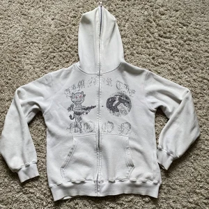 Vit hoodie Aim For The Moon  - Vit hoodie från Aim For The Moon med dragkedja, huva. Framsidan har ett tryck med en tecknad figur och texten 'Aim For The Moon' med mjuk insida